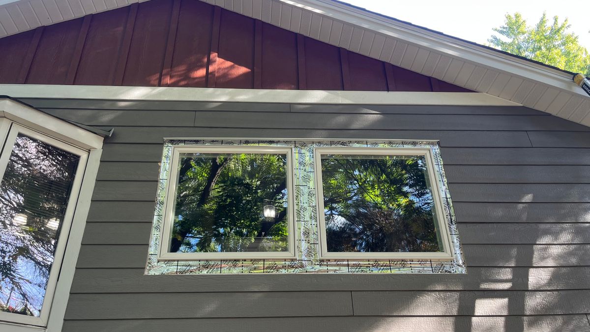 New charcoal LP SmartSide lap siding with barn-red board and batten gable accents and flashed Andersen windows in Minnetonka, MN