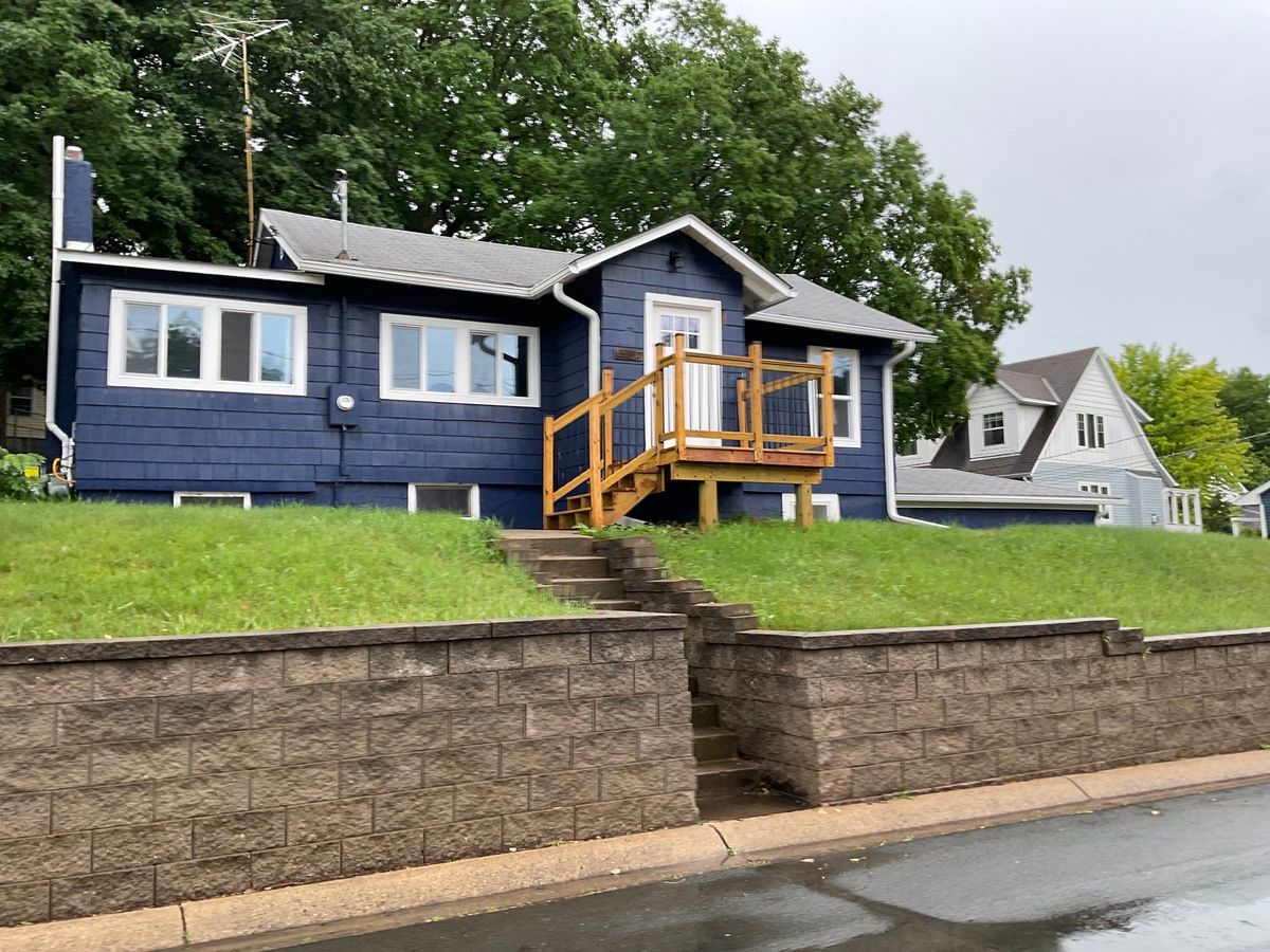 Completed navy LP SmartSide siding, white window trim, and wood entry deck in Mound, MN