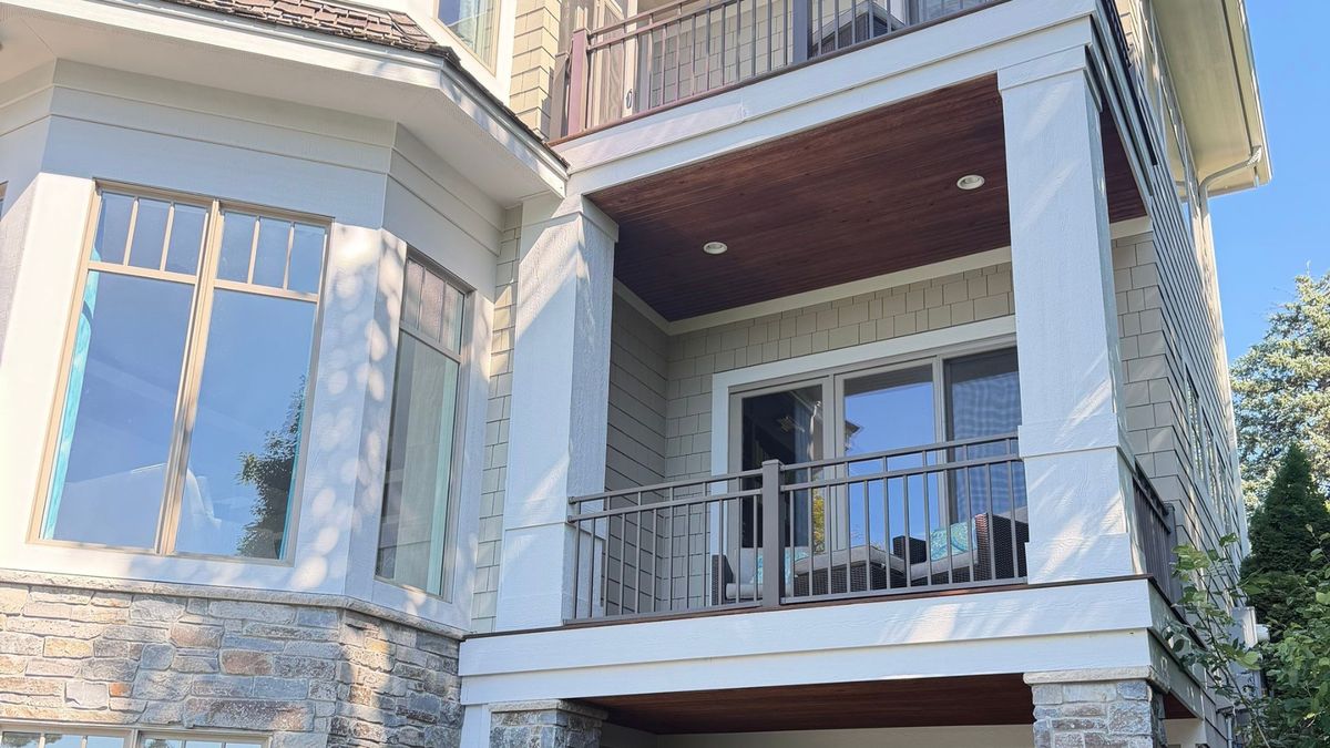 Second-story covered deck with stained wood ceiling, shake siding, and stone veneer in Wayzata, MN